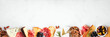 Assortment of charcuterie cheeses, meats and appetizers. Top view bottom border on a white marble background with copy space.