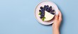 Woman s perspective of holding cheesecake slice with blueberries on plate With copyspace for text