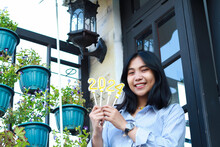 Happy Asian Young Woman Hipster Looking To Camera With Holding 2024 Number Candle Celebrating New Year Eve, Beautiful Female Standing In Front Of Vintage House Outdoor Garden With Low Angle View