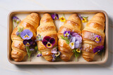 Freshly baked croissants decorated with edible pansy flowers