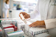 © Marko Geber - Close up of a pharmacist stacking medication in a row at the pharmacy
