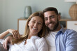 © fizkes - Happy handsome husband and beautiful wife head shot home portrait. Joyful attractive family married couple looking at camera with toothy smiles, laughing, talking on video call