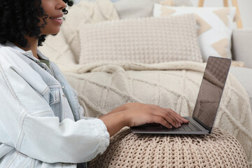 Poster - Woman using laptop on pouf at home, closeup