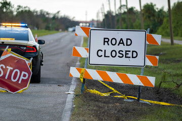 Wall Mural - Police patrol car at warning roadworks sign and safety barrier on city street during maintenance repair work