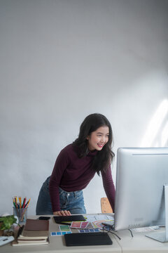 Graphic designer freelance women reading data to thinking creative ideas for logo brand while typing on computer and working to designing about graphic design with technology equipment in home studio
