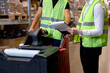 © alfa27 - warehouse workers men in reflective jackets pulling a pallet truck and talking while standing among shelves in retail warehouse logistics, distribution center. male holding clipboard, cargo control