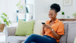 © Anela R/peopleimages.com - Relax, phone chat or black woman on sofa in communication in house living room. Smile, scroll or happy African person texting or reading online gossip on a mobile app discussion on couch at home