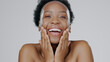 Face touch, skincare and funny black woman in studio isolated on a gray background. Portrait, hands and natural beauty of model laughing in spa facial treatment, wellness or cosmetics for skin health