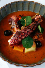 Sticker - grilled octopus with tomato sauce and vegetables. a glass of whi