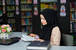 © Cavan - Muslim woman reading books in public library