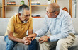 © aLListar/peopleimages.com - Men, sofa and support with friends in communication, hand gesture and grief with pain or loneliness. Elderly men, diversity and conversation on mental health or emotional counselling on sad with loss