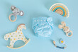 Flat lay with reusable cloth baby diaper, toys and accessories. Eco friendly nappy on blue pastel background. Sustainable lifestyle, zero waste idea