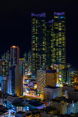 Wall Mural - Busan City skyline, skyscrapers, and modern buildings at night, illuminated in vibrant colors over the Haeundae Beach in Kyongsang Namdo, South Korea