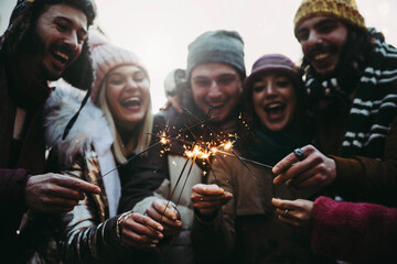 Wall Mural - Happy friends celebrating new year eve with sparklers - Cheerful family celebrate Christmas holiday with fireworks