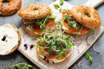 Wall Mural - Smoked salmon and soft cheese seeded bagel with pea and purple reddish shoot salad and red onion. Protein packed breakfast concept