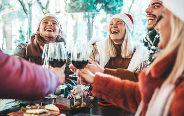 Poster - Happy family wearing santa claus hat having Christmas dinner party- Cheerful group of friends sitting at restaurant dining table celebrate xmas holiday cheering red wine glasses together