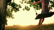 Funny Little Girl Plays Swings Under Old Tree In Country Garden At Sunset Time