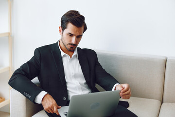 Man in office businessman sitting at desk and working in laptop and talking on phone, modern suit, finance and startup concept and data analysis, working lifestyle in bright office.