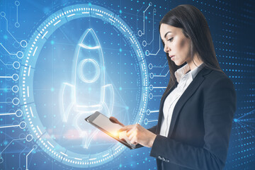 Aufkleber - Attractive young european businesswoman using tablet with creative digital circular rocket hologram with circuit lines on blue background. Digital business and startup banking concept.