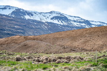 Snow mountain range at Seydisfjordur, Iceland with meadow and sand mountain in front