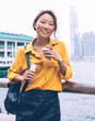 © BullRun - Happy Asian young woman smiling at city embankment