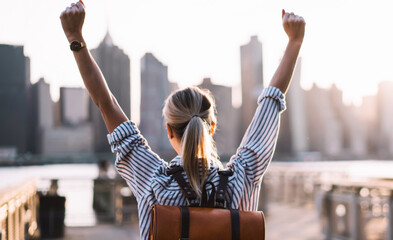 Wall Mural -  back view of successful female tourist with rucksack on back raising hands