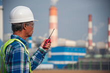Senior Electrician Engineer Man Hand Holding Red Walkie Talkie Communicate Wear White Hardhat At Power Stations Manufacturing Electrical Plant. Technician Worker Blue Hard Hat Helmet Engineer Industry