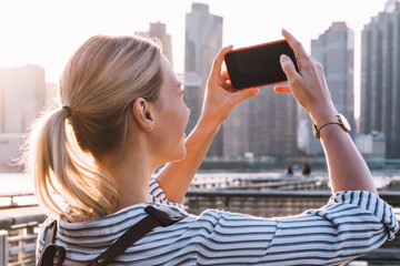 Wall Mural - female tourist testing cellphone while taking photos of city