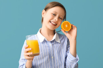 Wall Mural - Little girl with glass of juice and orange on blue background