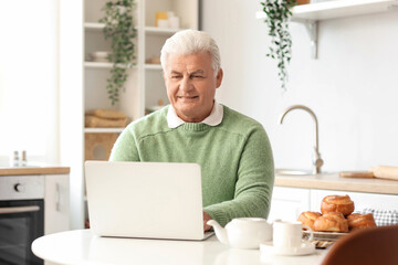 Sticker - Senior man using laptop in kitchen