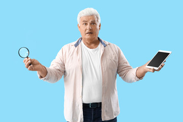 Poster - Confused senior man with magnifier and tablet computer on blue background