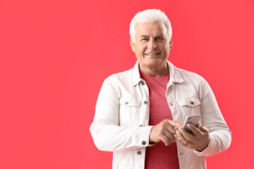 Poster - Senior man using mobile phone on red background