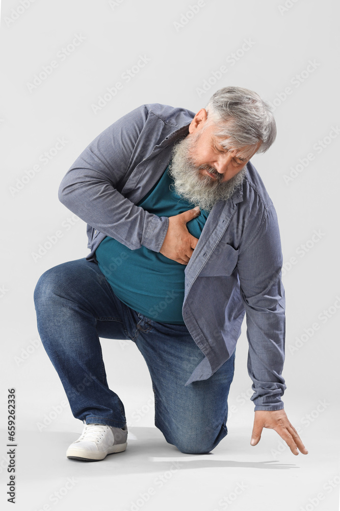 Senior man having heart attack on light background