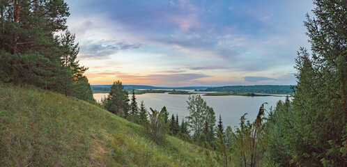 Wall Mural - Sunrise on the river bank sun through the trees, beautiful clouds panoramic view.