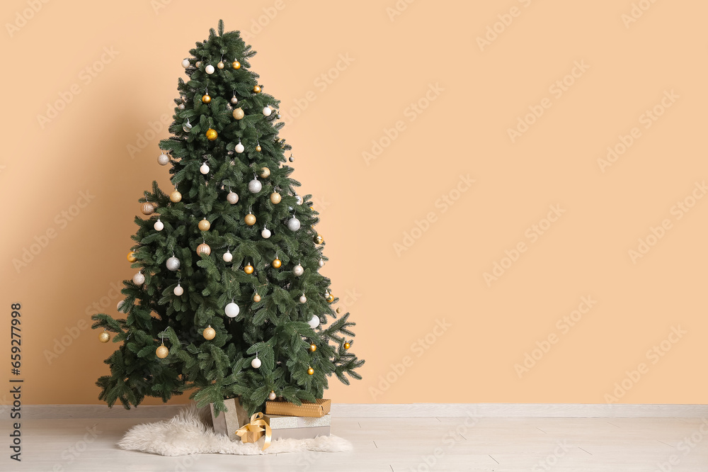 Christmas tree decorated with baubles near beige wall