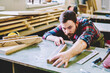 © BullRun - Bearded carpenter measuring board on workbench