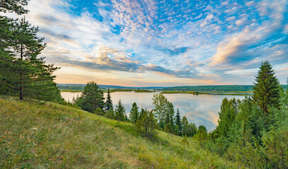Wall Mural - Sunrise on the river bank sun through the trees, beautiful clouds panoramic view.