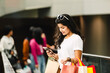 Beautiful asian woman using smart phone with shopping bag in the city
