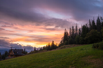 Wall Mural - beautiful dramatic coloured sky over a meadow in the mountains.
