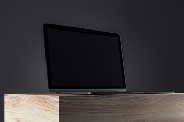 Poster - Close up of blank laptop monitor on wooden surface and gray wall background. Product presentation and advertisement concept. Mock up, 3D Rendering.