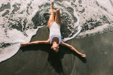 Carefree woman lying on black sand at beach