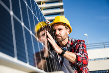 Confident Engineer Wearing Hardhat Examining Solar Panel