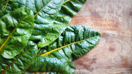 Wall Mural - Fresh raw swiss rainbow chard leaves on wooden background. Top view