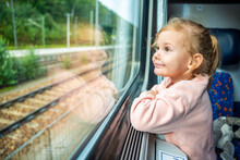 Happy Little Girl Looking Out Train Window Outside, While It Moving. Traveling By Railway In Europe