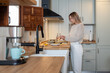 © Bisual Photo - Caucasian woman in casual outfit standing at counter and preparing healthy meal for breakfast in modern kitchen