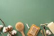 Eco-Friendly Essentials: Top view of sustainable bamboo toothbrushes, cotton buds, anticellulite brush, homemade soap, and more on green backdrop with space for your message or advertising
