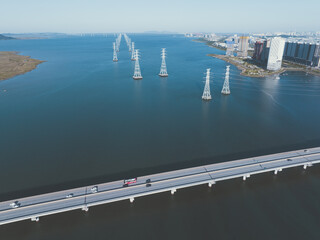 Cars and high-voltage transmission towers passing over a bridge over the sea