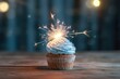 Birthday cupcake with a candle and festive tinsel decoration on a blue background