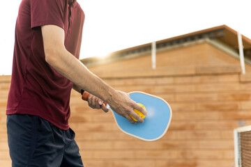 Wall Mural - Profile view of an unrecognizable senior adult male in sportswear is about to make a serve during a pickleball match. Pickleball concept.Men playing pickleball at sunset.