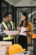 © NINENII - Businessman working as a team discussing data working and tablet, laptop with on on architectural project at construction site at desk in office.